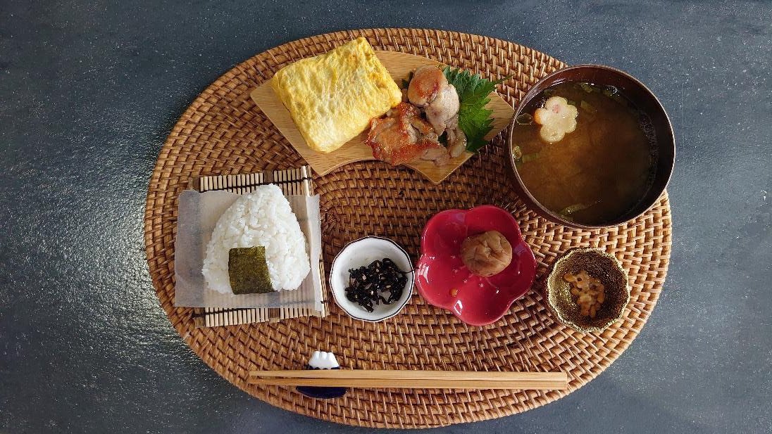 おにぎり・味噌汁・だし巻き玉子・照り焼きチキン・梅干し・納豆・佃煮を盛り付けた日本の朝ごはん(一汁三菜)